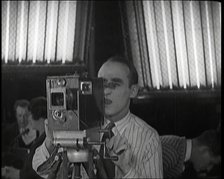 A Male Cameraman Films a Scene Whilst Lights Illuminate Behind Him, 1920s. Creator: British Pathe Ltd.