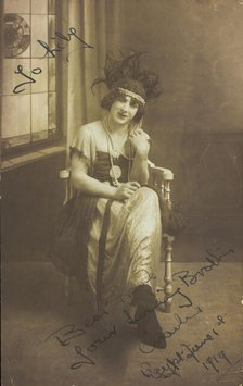 A man in drag (Charlie) sits face-on, wearing detailed costume, with a window painted..., 1919. Creator: Unknown.