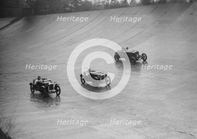 Two Austin 7s and an unidentified car racing at a BARC meeting, Brooklands, Surrey, 1931 Artist: Bill Brunell.