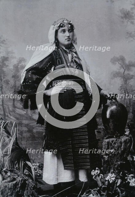 A Bulgarian woman in national dress with a water jug, early 20th century. Creator: Unknown.