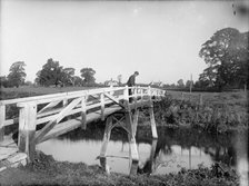 A man looking over the Eisey Footbridge into the River Thames, Cricklade, Wiltshire, c1860-c1922. Artist: Henry Taunt