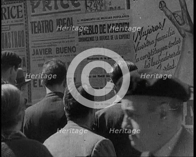Residents of Madrid Looking at Government Posters on a Wall, 1937. Creator: British Pathe Ltd.