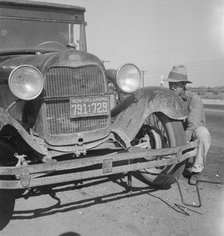 Migrant worker from Oklahoma repairing tire on California highway, 1936. Creator: Dorothea Lange.
