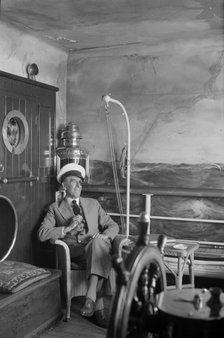 A man in a sailor's cap and eyepatch sits in a reconstructed ship's cabin, c1945-c1965. Artist: SW Rawlings