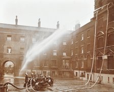 Firemen demonstrating hoses worked by a petrol motor pump, London Fire Brigade Headquarters, 1909. Artist: Unknown.