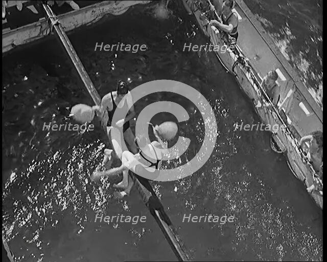 Two Male Civilians in Swim Suits Sitting on a Pole and Enjoying a Pillow Fight in Front..., 1931. Creator: British Pathe Ltd.