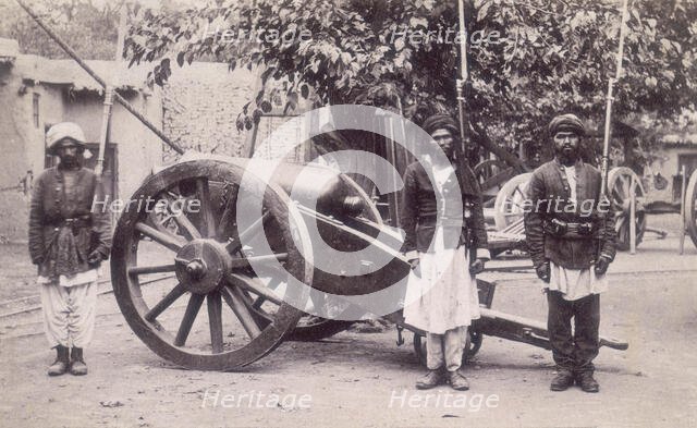 Three Afghan soldiers standing next to a cannon, Afghanistan, 1880s. Creator: Unknown.