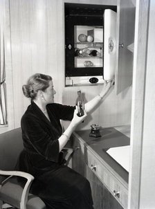 Woman using a compact fridge, possibly on board a ship, c1955.  Creator: Arthur Charles Kirby Ware.