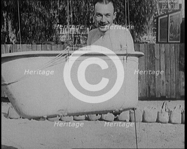 A Male Civilian Sitting in a Bath Before the Bath is Lifted Off the Ground By a Hot Air..., 1920s. Creator: British Pathe Ltd.