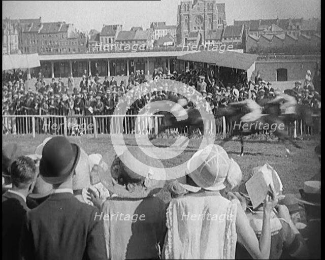 A Large Crowd of Civilians Wearing Smart Outfits and Hats Watching a Horse Race, 1920. Creator: British Pathe Ltd.