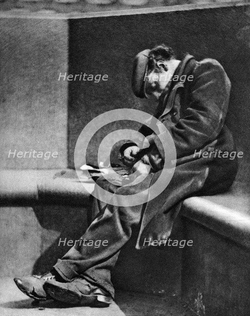 A man sleeping on Blackfriars Bridge, London, 1926-1927.Artist: Walter Benington