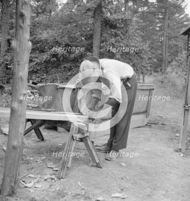 Zollie Lyons repairing the tobacco sleds at...harvest season, Wake County, North Carolina, 1939. Creator: Dorothea Lange.