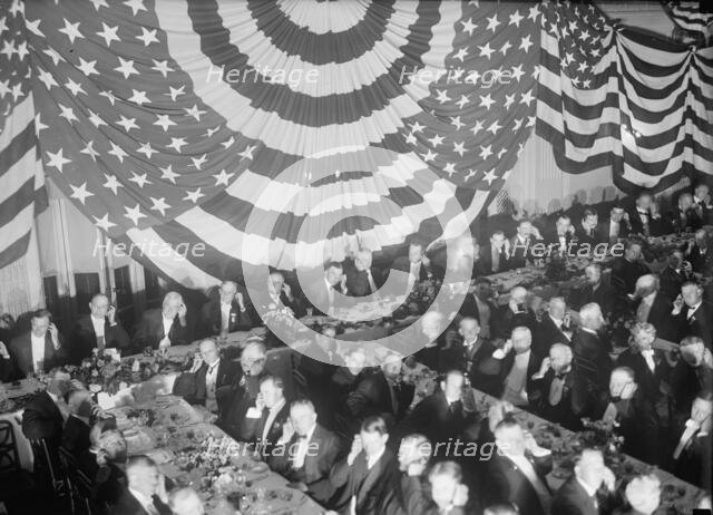 Banquet Scene with Flag Draping And Men Seated Holding Up Listening Device To One Ear, c1913-1917. Creator: Harris & Ewing.