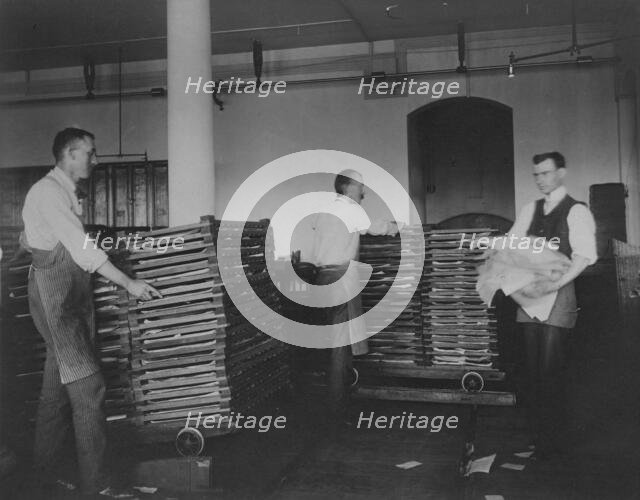 Workers moving newly printed currency into a drying box where sheets will dry before...c1890. Creator: Frances Benjamin Johnston.
