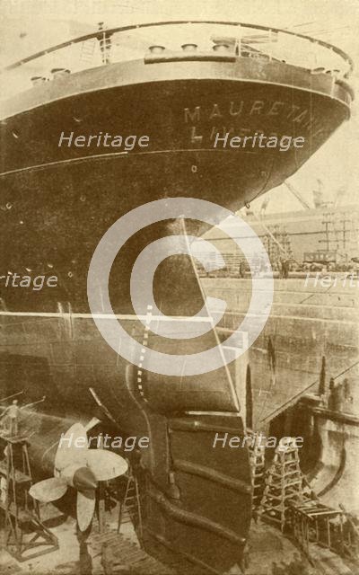 'At Work on the Stern of the "Mauretania", in Dry Dock', c1930. Creator: Unknown.