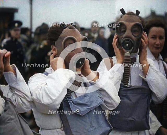 A Close up of Three Female Civil Defence Volunteers in White Boiler Suits Putting on Gas..., 1938. Creator: British Pathe Ltd.