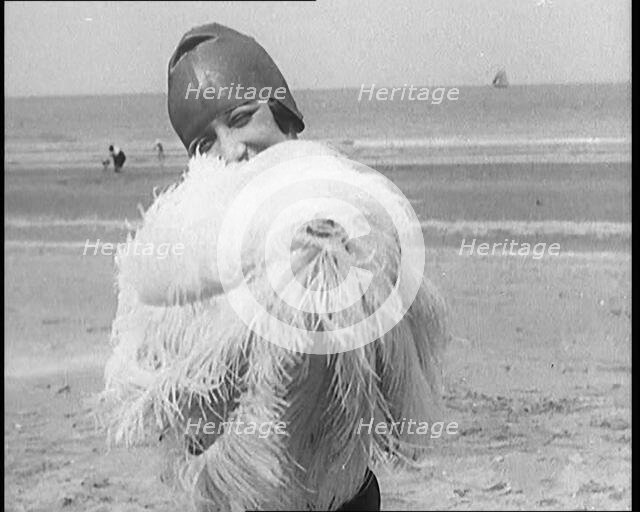 Female Civilian Wearing a Swimsuit Holding a Feathered Parasol at the Beach, 1920. Creator: British Pathe Ltd.
