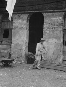 Man cleaning out a small building, New Orleans or Charleston, South Carolina, between 1920 and 1926. Creator: Arnold Genthe.