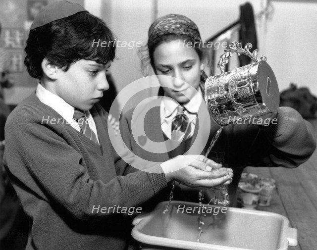Jewish children performing ritual hand-washing, April 1991. Artist: Sidney Harris