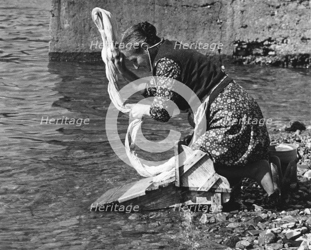 Woman washing clothes in a river, Portugal, 1973. 