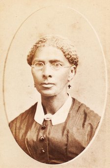 Studio portrait of woman wearing glasses and cross-shaped earrings, c1880-c1889. Creator: George Daniels Morse.