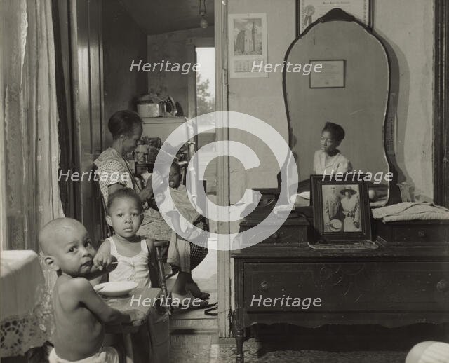 Dinner time at the home of Mrs. Ella Watson, a government charwoman, Washington, D.C., 1942. Creator: Gordon Parks.