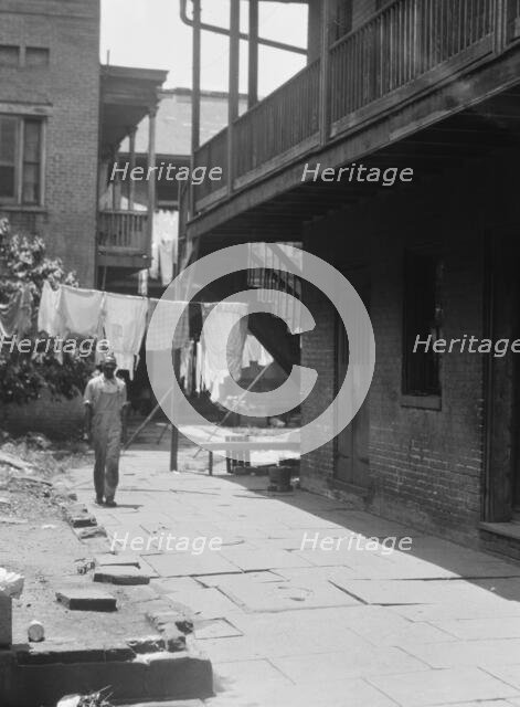 Man standing in a courtyard, New Orleans, between 1920 and 1926. Creator: Arnold Genthe.