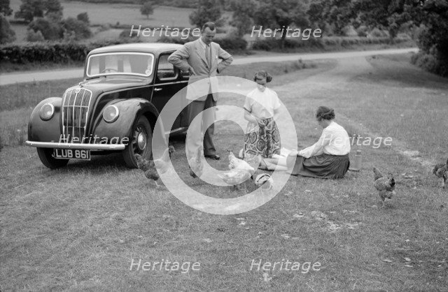 A family group feed chickens beside their car, c1945-c1965. Artist: SW Rawlings