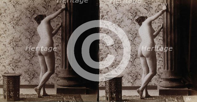 A young woman posing naked in a photographic studio, with her back to the camera looking..., c1900. Creator: Unknown.