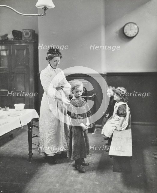 Nurse examining children before 'cleansing', Chaucer Cleansing Station, London, 1911. Artist: Unknown.