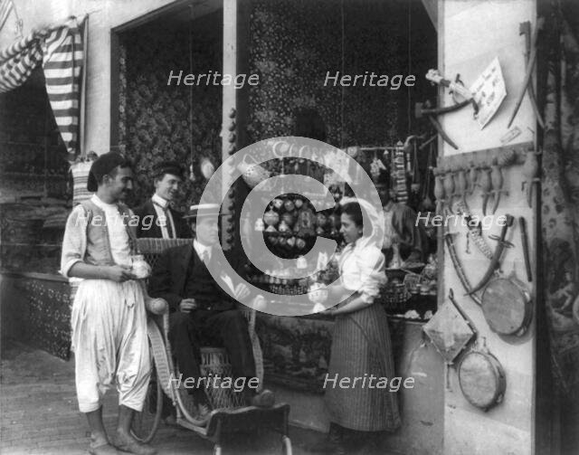 Pan-American Exposition, Buffalo, N.Y., 1901: Man in wheeled chair at souvenir shop with 4..., 1901. Creator: Frances Benjamin Johnston.