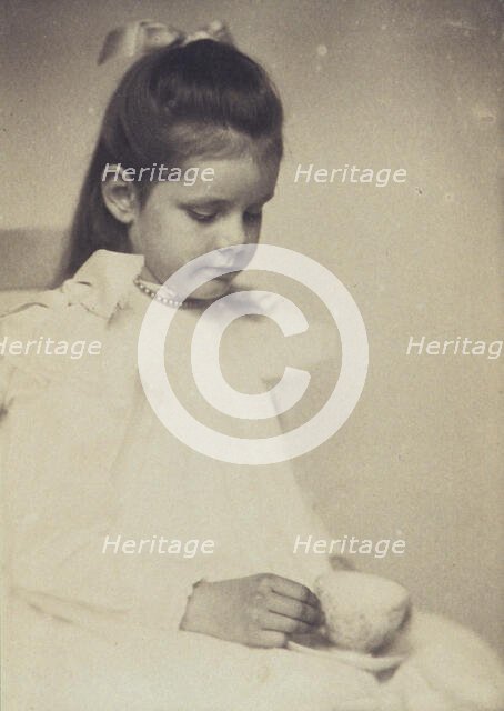 Young girl in white dress, seated holding teacup and saucer, c1900. Creator: Anne K Pilsbury.
