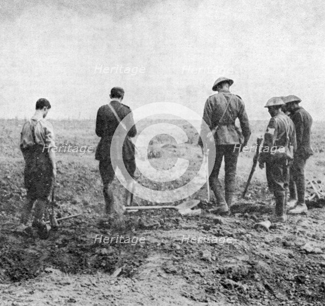 Chaplain conducting burial service in the field while burial party pay their respects, c1916. Artist: Unknown