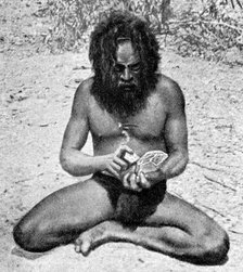 A man from the Warramunga tribe making a stone axe head, Australia, 1922.Artist: Spencer and Gillen