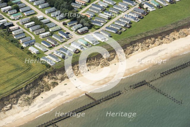 Coastal erosion between a caravan park and the sea defences at Corton Cliffs, Suffolk, 2019. Creator: Historic England.