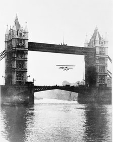 Biplane flying under Tower Bridge, Stepney, Tower Hamlets, London. Artist: Unknown