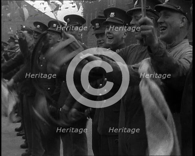 Uniformed British Soldiers Cheering and Smiling Whilst Waving Flags, 1937. Creator: British Pathe Ltd.