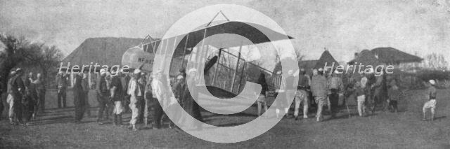 'La retraite de nos aviateurs par l'Albanie; Biplan entoure par la population masculine..., 1916. Creator: Unknown.