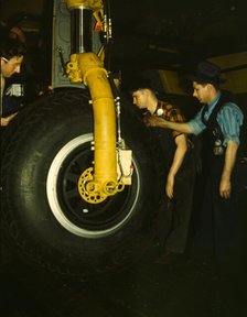 Inspecting of landing wheel of the transport planes at Willow Run, between 1941 and 1945. Creator: Howard Hollem.