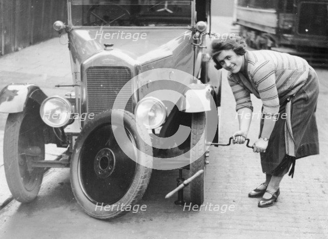 Ivy Cummings changing a tyre on a 1925 Singer 10/26, London, c1925. Artist: Unknown