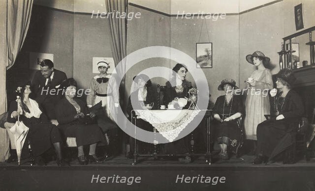 Amateur actors, some in drag, are having tea on stage, [between 1920 and 1929?]. Creator: Unknown.