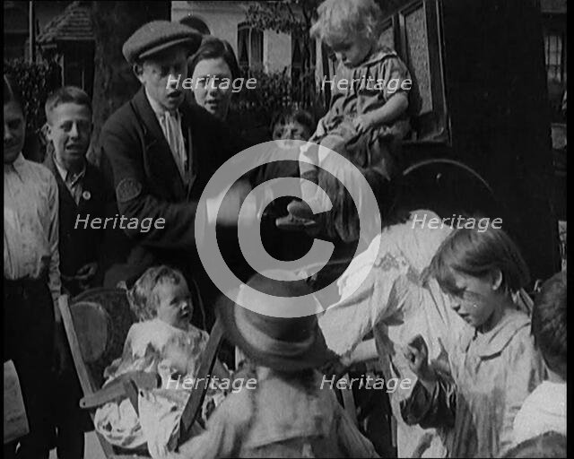 A Group of Civilian Children Dancing in Front of a Hurdy Gurdy Watched by a Small Crowd..., 1920. Creator: British Pathe Ltd.