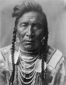 Strike On his Head, Crow Indian, Montana, head-and-shoulders portrait, facing front, loose..., c1908 Creator: Edward Sheriff Curtis.