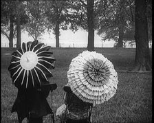 Female Civilians Holding Ornate Parasols in a Park, 1920. Creator: British Pathe Ltd.