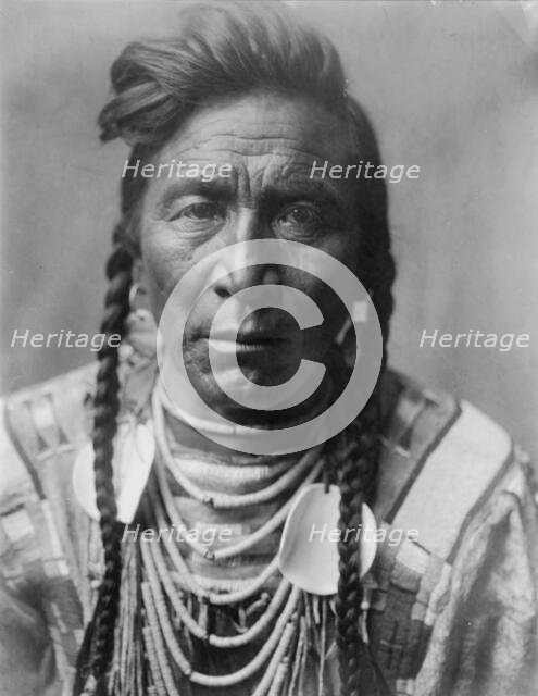 Strike On his Head, Crow Indian, Montana, head-and-shoulders portrait, facing front, loose..., c1908 Creator: Edward Sheriff Curtis.