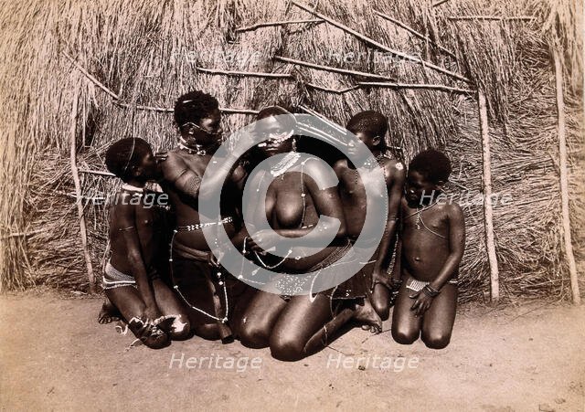 Africa: African women adorning themselves with beads, outside a kraal hut, 19th century. Creator: Unknown.