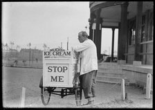 An Eldorado ice cream seller standing beside his tricycle cart outside a pavilion, 1930s. Creator: Charles William  Prickett.