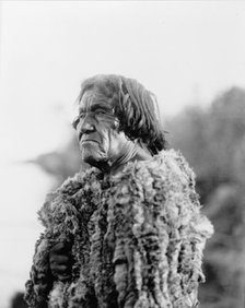 Mohave man, half-length portrait, facing left wearing "primitive" robe of rabbit skin, 1907. Creator: Edward Sheriff Curtis.