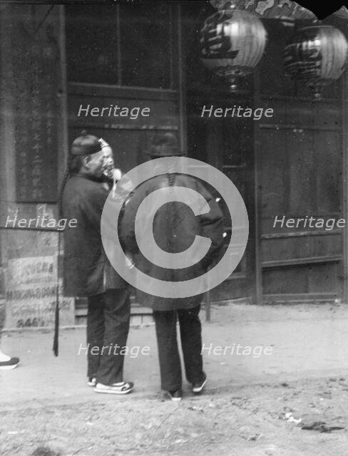 Two men, one holding a child, standing in the street, Chinatown, San Francisco, c1896-1906. Creator: Arnold Genthe.