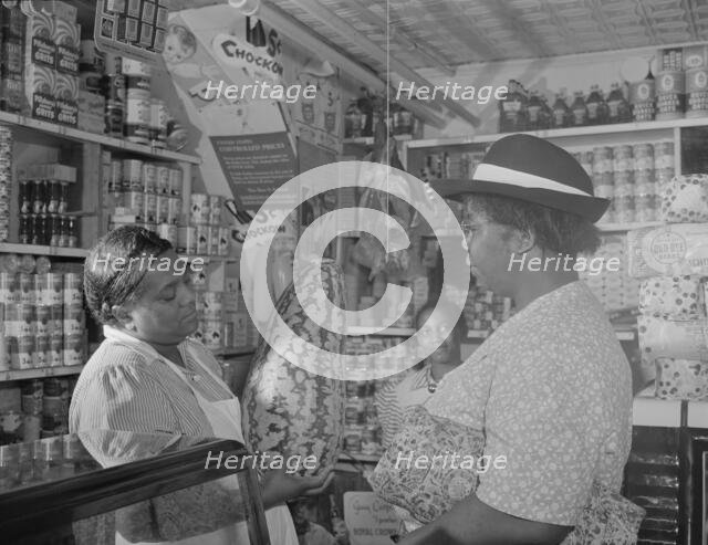Housewife bargaining in the store owned by Mr. J. Benjamin, Washington, D.C., 1942. Creator: Gordon Parks.